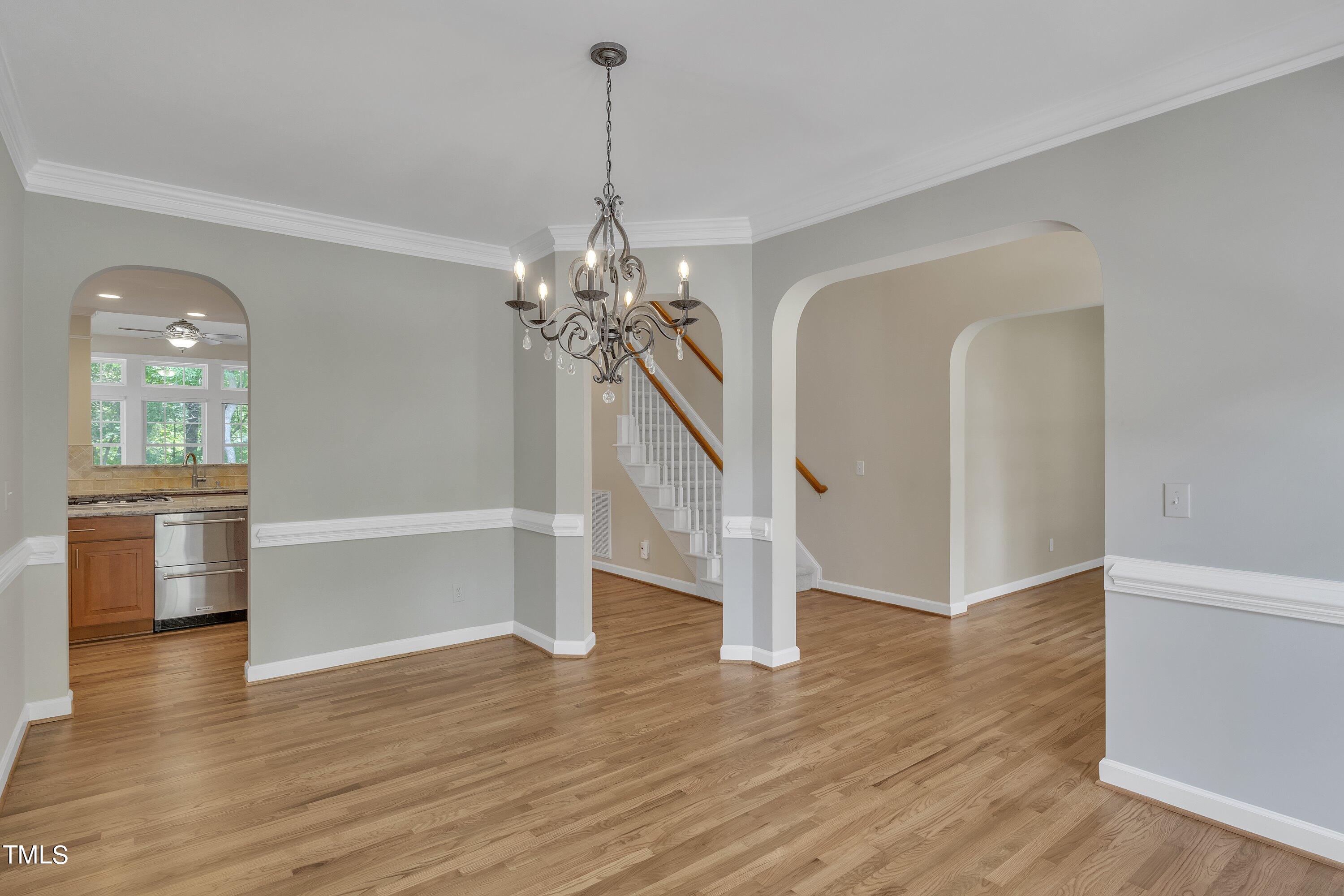 12208 Jasmine Cove Way Raleigh, NC 27614 - Photo 8 of 57 a view of an empty room with wooden floor and kitchen view