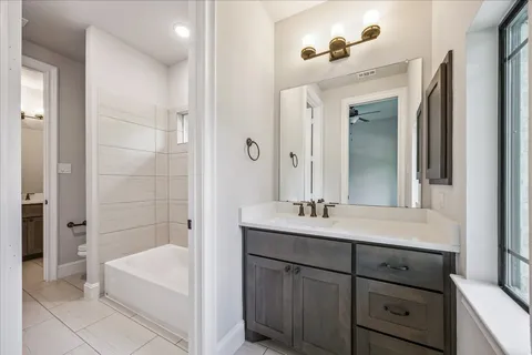 a en suite bathroom with a double vanity sink a large mirror and a bathtub