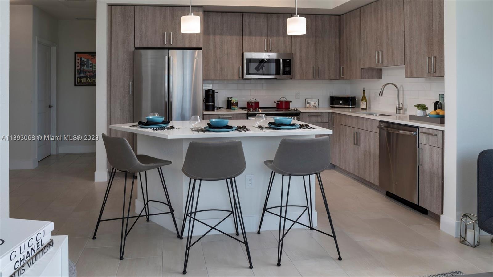 2701 Biscayne Boulevard, Unit 6217 Miami, FL 33137 - Photo 9 of 45 a kitchen with stainless steel appliances kitchen island a table chairs microwave and sink