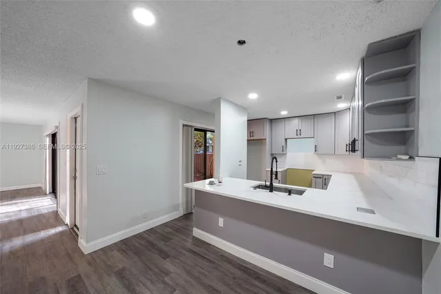 a room with kitchen island a sink and wooden floor