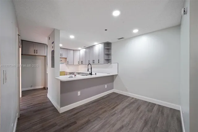 a large room with kitchen island a sink dishwasher a refrigerator and wooden floor