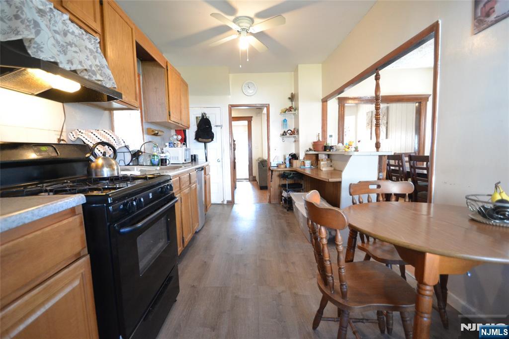 655 Chestnut Street Kearny, NJ 07032 - Photo 12 of 31 a kitchen with stainless steel appliances granite countertop a stove top oven a sink dishwasher and a dining table with wooden floor