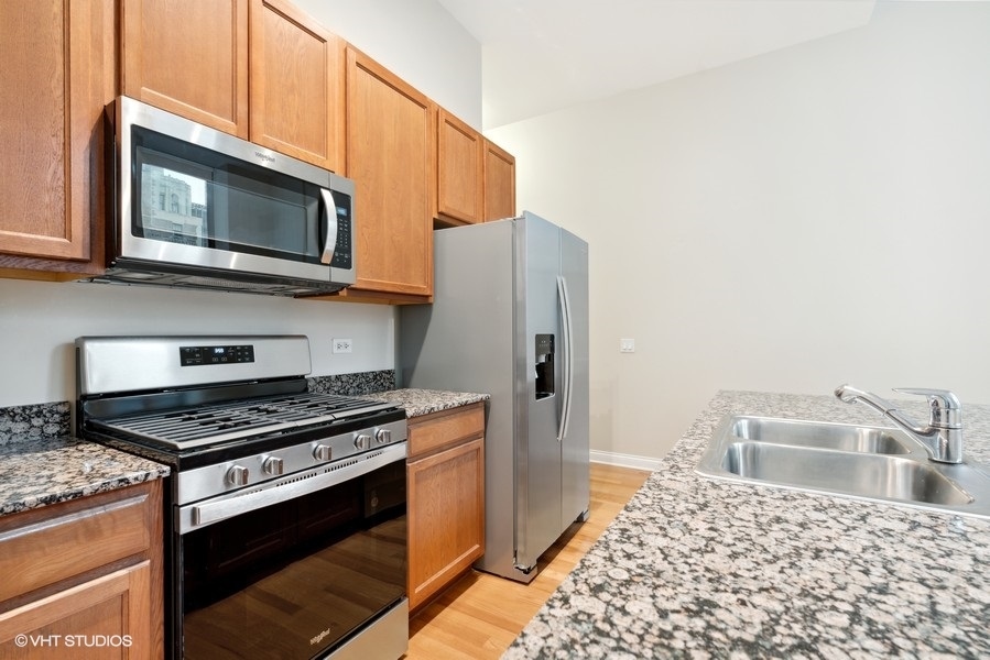 8 West Monroe Street, Unit 500 Chicago, IL 60603 - Photo 7 of 14 a kitchen with stainless steel appliances granite countertop a stove a microwave and a refrigerator