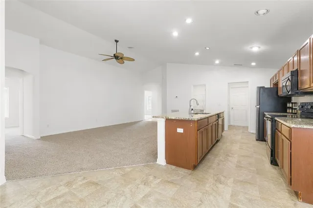 a large kitchen with stainless steel appliances granite countertop a sink a stove a refrigerator a center island with wooden floor