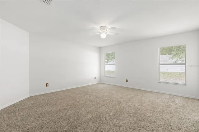 an empty room with a window and a ceiling fan