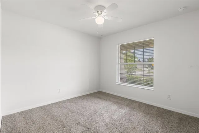 an empty room with a window and a fan