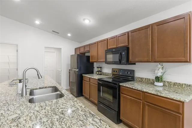 a kitchen with stainless steel appliances granite countertop a sink a stove a refrigerator cabinets and a counter top space