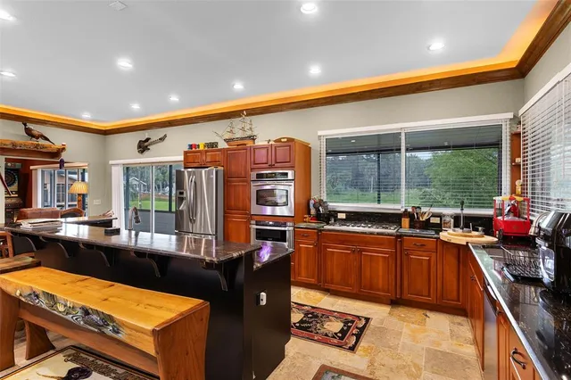 a kitchen with stainless steel appliances kitchen island granite countertop a sink and a stove