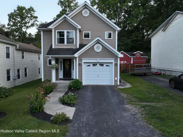 a front view of a house with a garden and trees