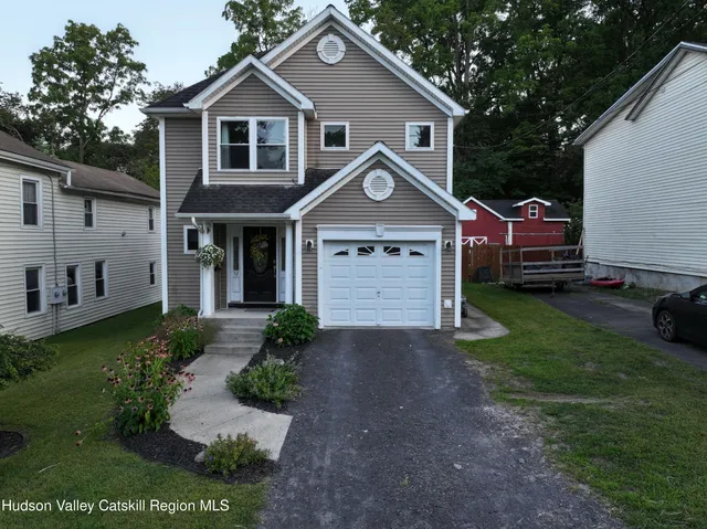 a front view of a house with a garden and trees