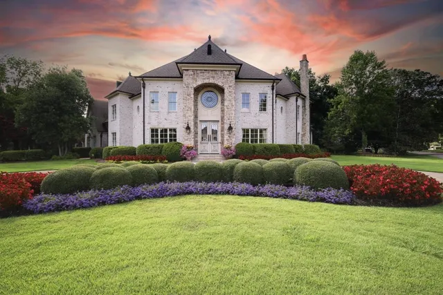 a front view of a house with a big yard and potted plants