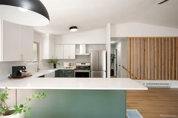 a kitchen with stainless steel appliances a refrigerator a stove a sink and white cabinets with wooden floor