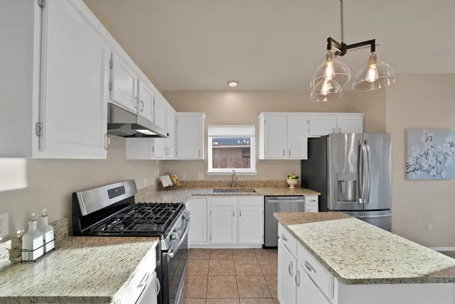 a kitchen with stainless steel appliances granite countertop a stove a sink dishwasher and a refrigerator