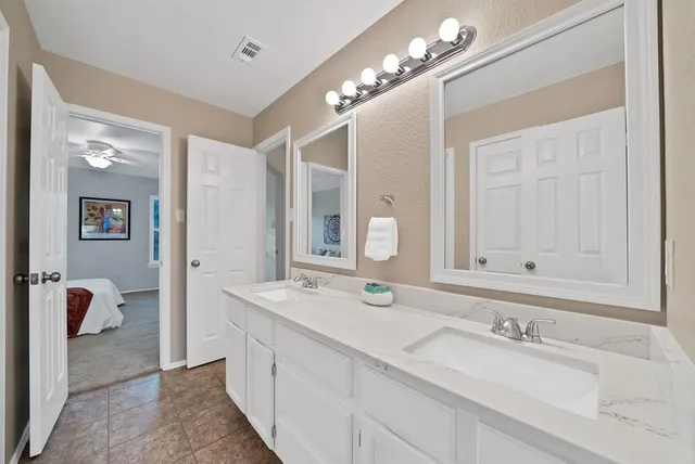 a spacious en suite bathroom with a double sink and mirror