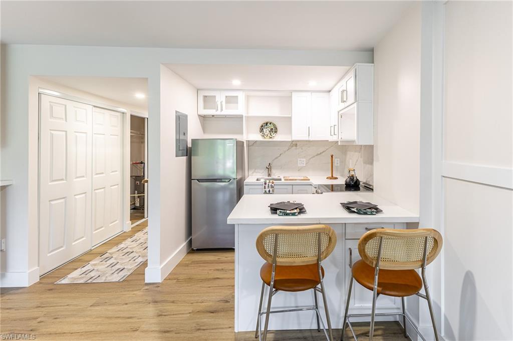 5 Bluebill Avenue, Unit 105 Naples, FL 34108 - Photo 12 of 26 a kitchen with stainless steel appliances granite countertop a stove a refrigerator and a dining table with wooden floor
