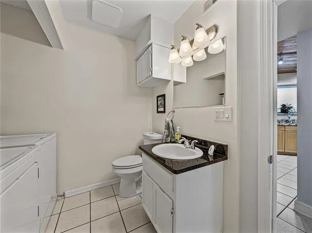 a bathroom with a granite countertop sink a toilet and a mirror