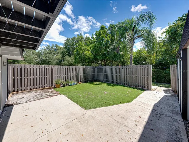 an aerial view of a residential houses with outdoor space and trees