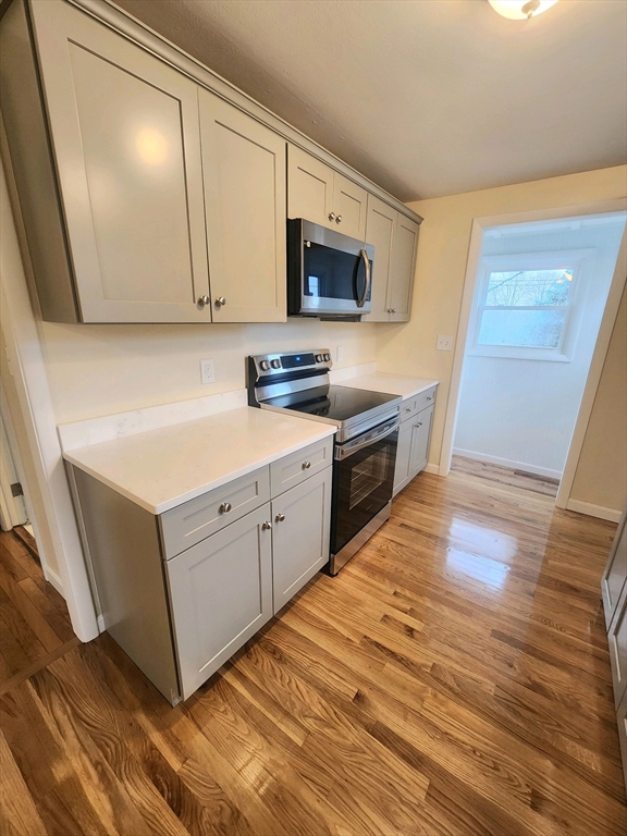 44 Bowes Avenue Quincy, MA 02169 - Photo 6 of 20 a kitchen with stainless steel appliances granite countertop a sink a stove top oven and wooden floors