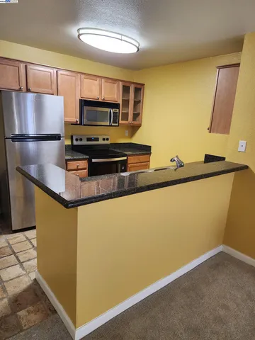 a kitchen with stainless steel appliances granite countertop a refrigerator a stove and a sink