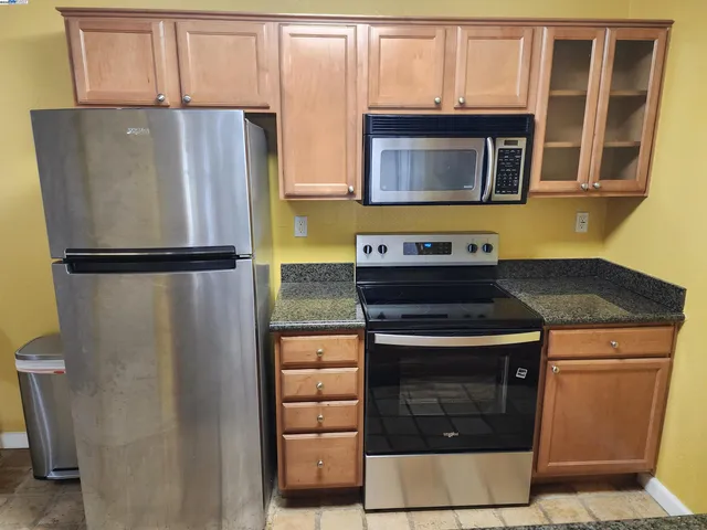 a kitchen with stainless steel appliances granite countertop a refrigerator and a stove top oven