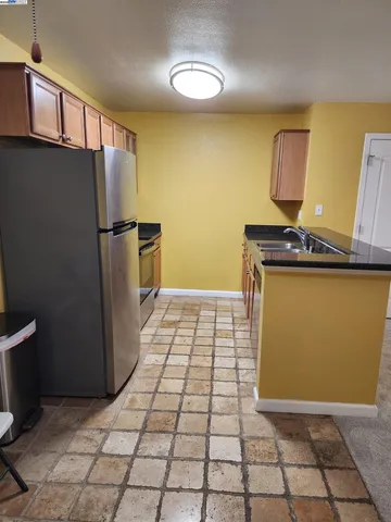 a view of a refrigerator in kitchen and an empty room