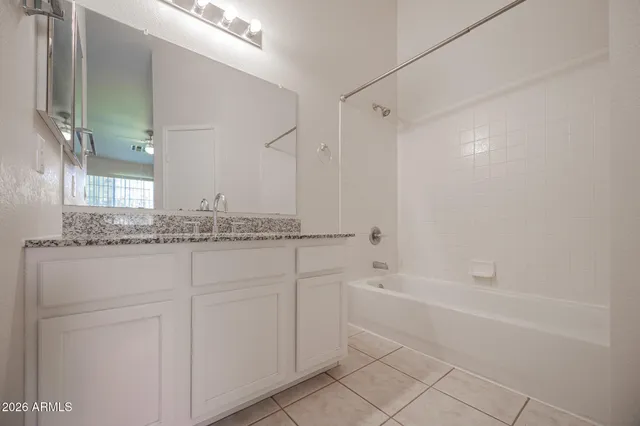 a bathroom with a granite countertop sink a mirror and a bathtub