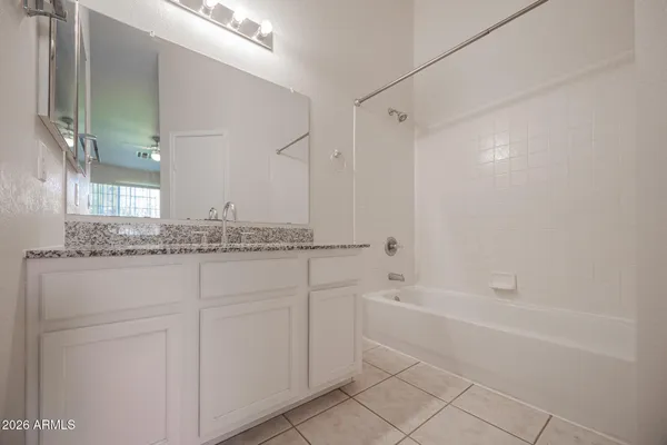 a bathroom with a granite countertop sink a mirror and a bathtub