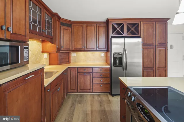 a kitchen with stainless steel appliances granite countertop a refrigerator a stove and a sink with wooden cabinets