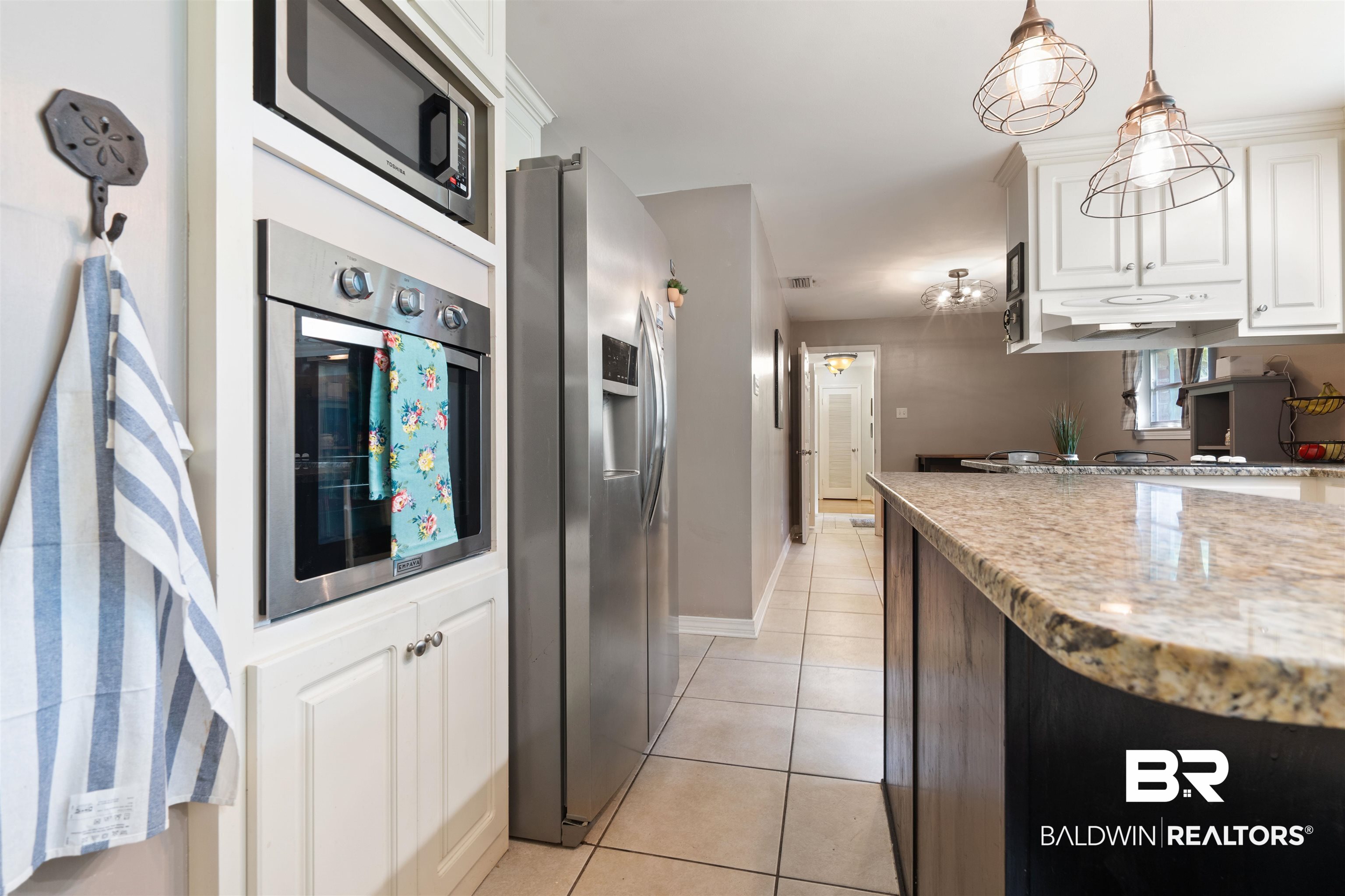 4051 East Canal Circle Mobile, AL 36619 - Photo 10 of 32 Kitchen with white cabinetry, light tile patterned floors, light stone counters, appliances with stainless steel finishes, and decorative light fixtures