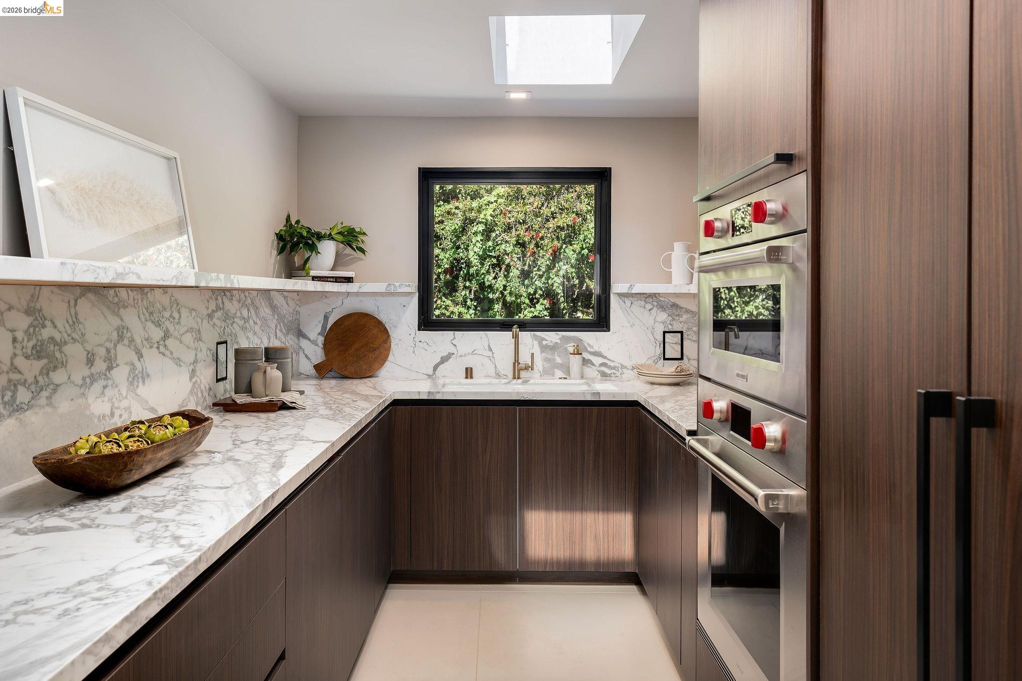 5645 Bacon Road Oakland, CA 94619 - Photo 39 of 94 Contemporary kitchen featuring wood-finish cabinetry, light-toned stone countertops, and a full-height stone backsplash