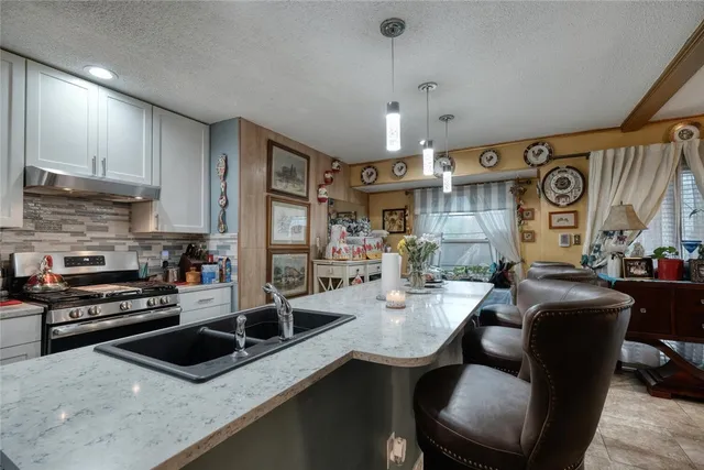 a kitchen with stainless steel appliances granite countertop a sink a stove top oven a counter space and cabinets