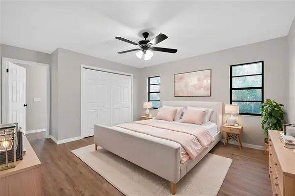 an empty room with wooden floor chandelier fan and windows