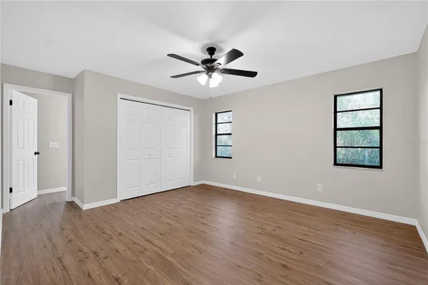 an empty room with wooden floor and ceiling fan
