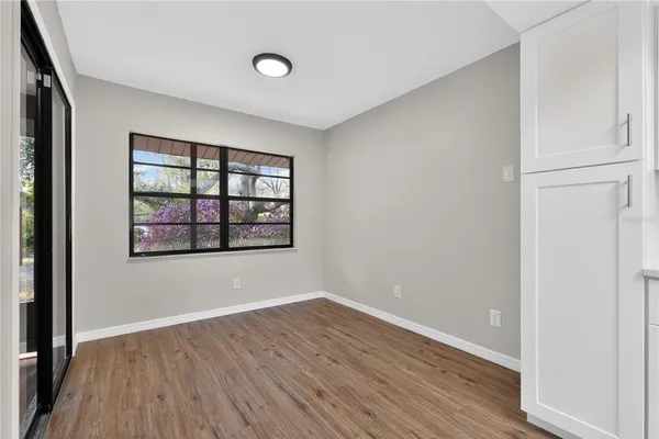 an empty room with wooden floor fan and windows