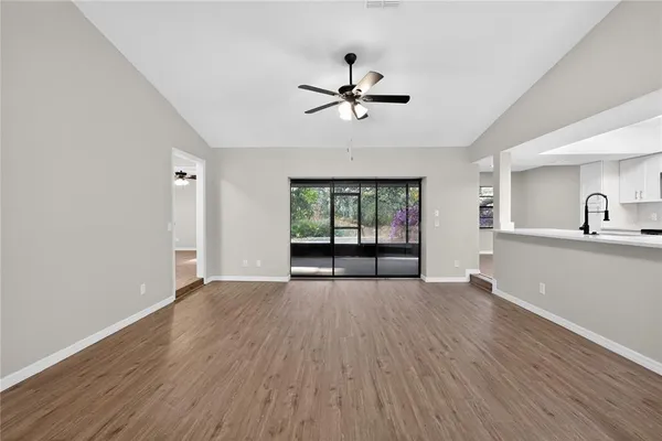 a view of a hallway with wooden floor and a kitchen