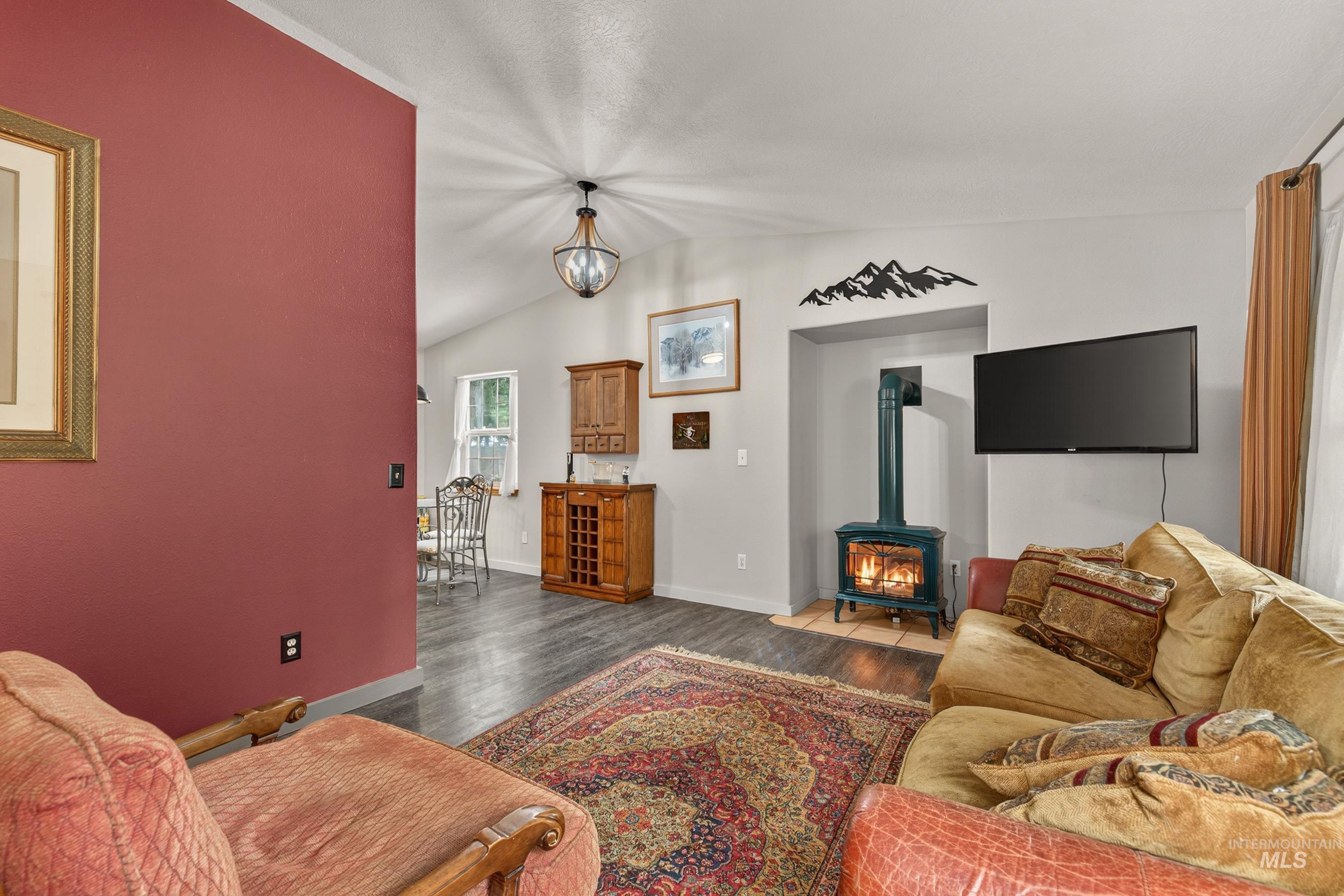 1801 Carico Road McCall, ID 83638 - Photo 6 of 30 Living area featuring a wood stove, dark wood-style floors, vaulted ceiling, and hanging lights