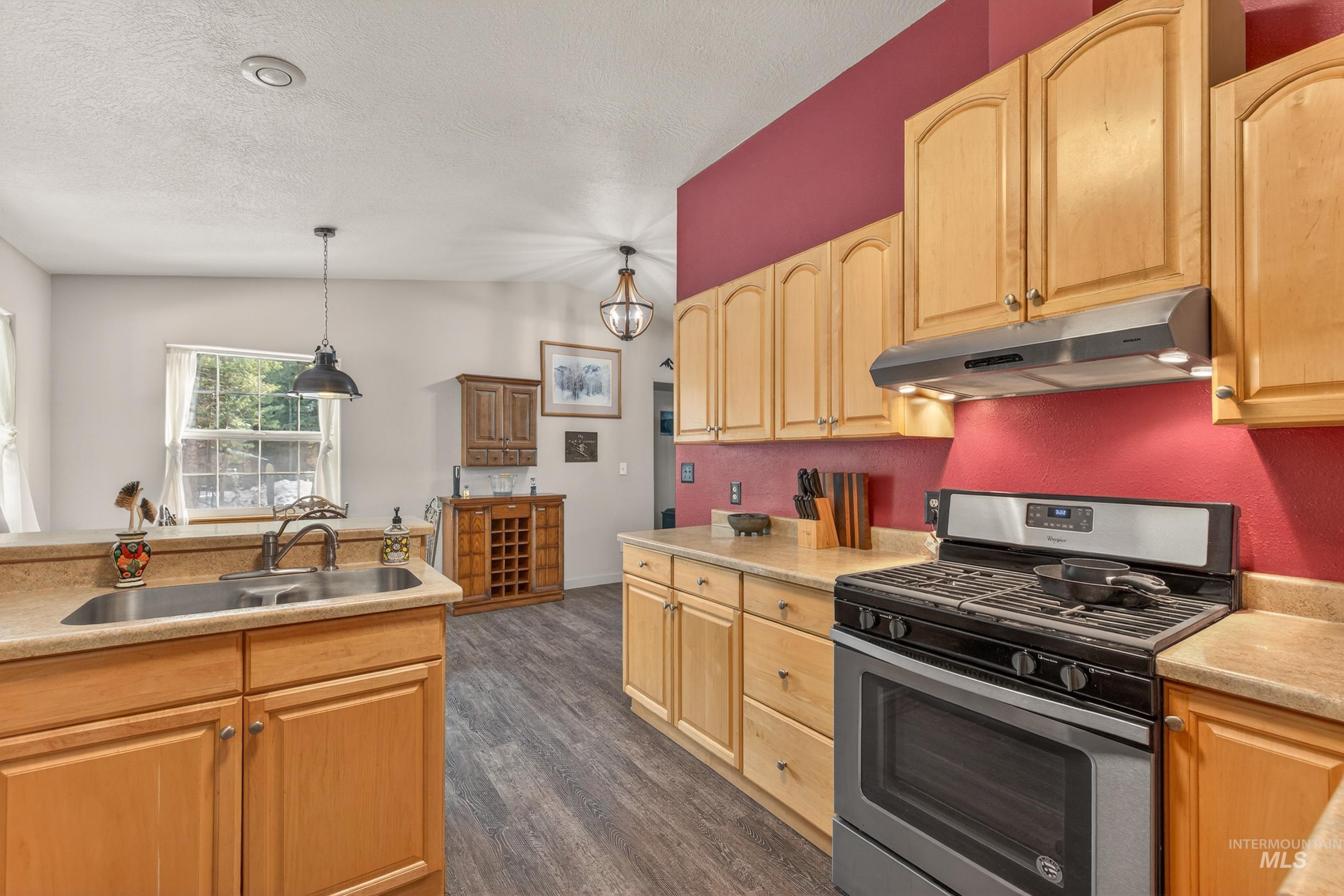 1801 Carico Road McCall, ID 83638 - Photo 7 of 30 Kitchen featuring stainless steel range with gas cooktop, light countertops, light wood finish cabinetry, dark wood-style flooring, and a textured ceiling