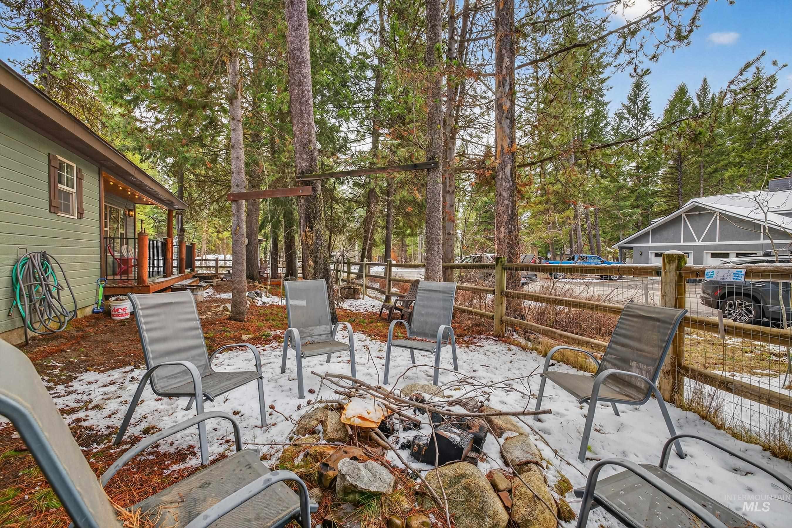 1801 Carico Road McCall, ID 83638 - Photo 10 of 30 Snow covered patio featuring a fenced backyard, a wooden deck, view of scattered trees, and a patio