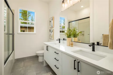 a bathroom with a double vanity sink toilet and mirror