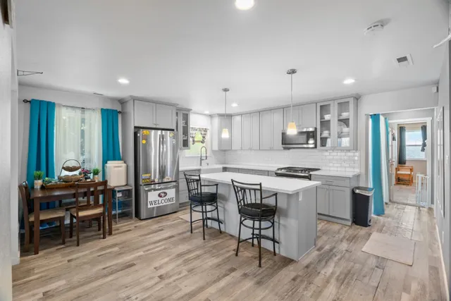 a kitchen with stainless steel appliances a dining table chairs stove refrigerator and cabinets