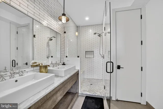 a bathroom with a double vanity sink a large mirror and shower