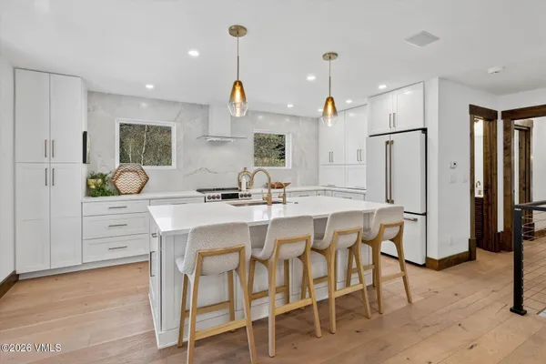 a kitchen with stainless steel appliances kitchen island granite countertop a dining table chairs and white cabinets
