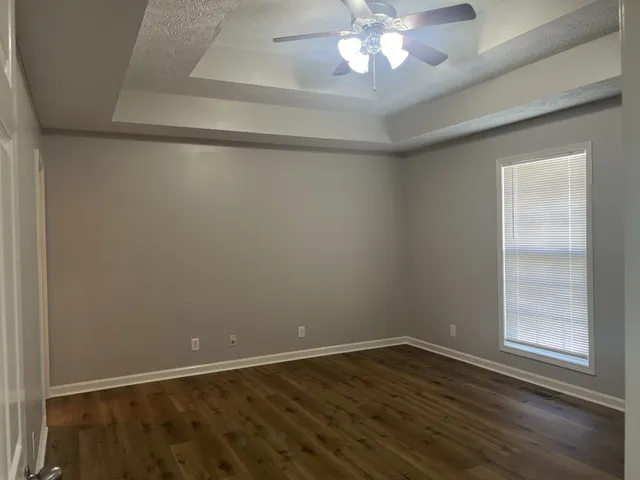 en empty room with wooden floor and fan