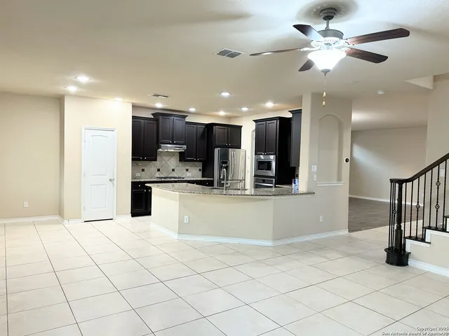 a kitchen with stainless steel appliances kitchen island granite countertop a refrigerator and a sink