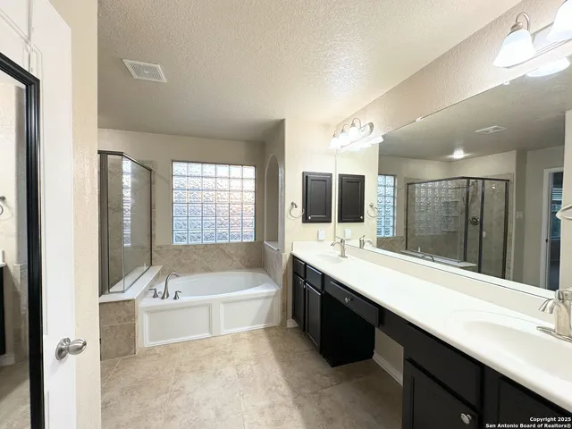 a bathroom with a large tub sink shower double vanity