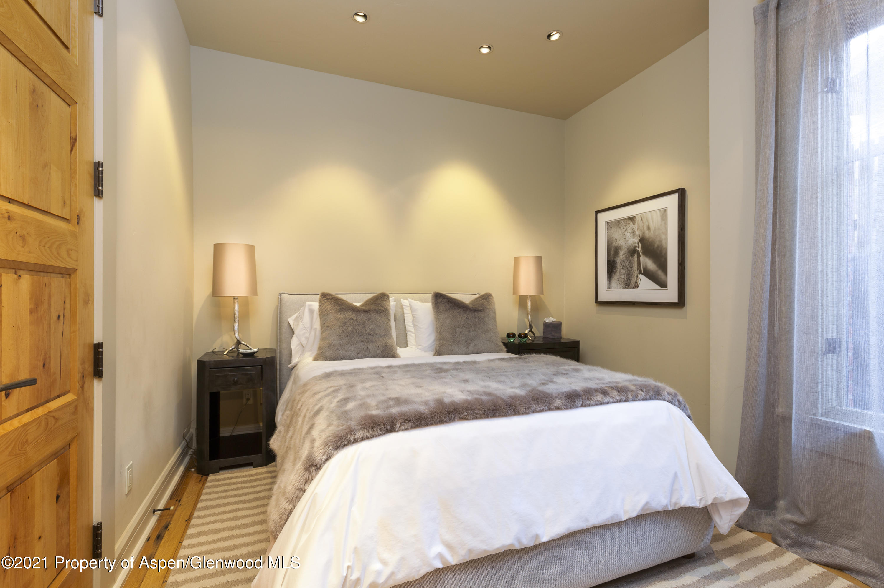 101 Founders Place, Unit 202 Aspen, CO 81611 - Photo 1 of 26 a spacious bedroom with a bed and a painting on the wall