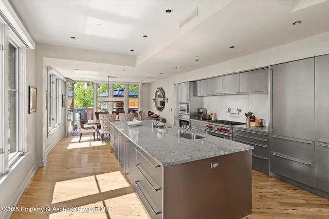 a large kitchen with kitchen island a large counter top space a sink a refrigerator and windows