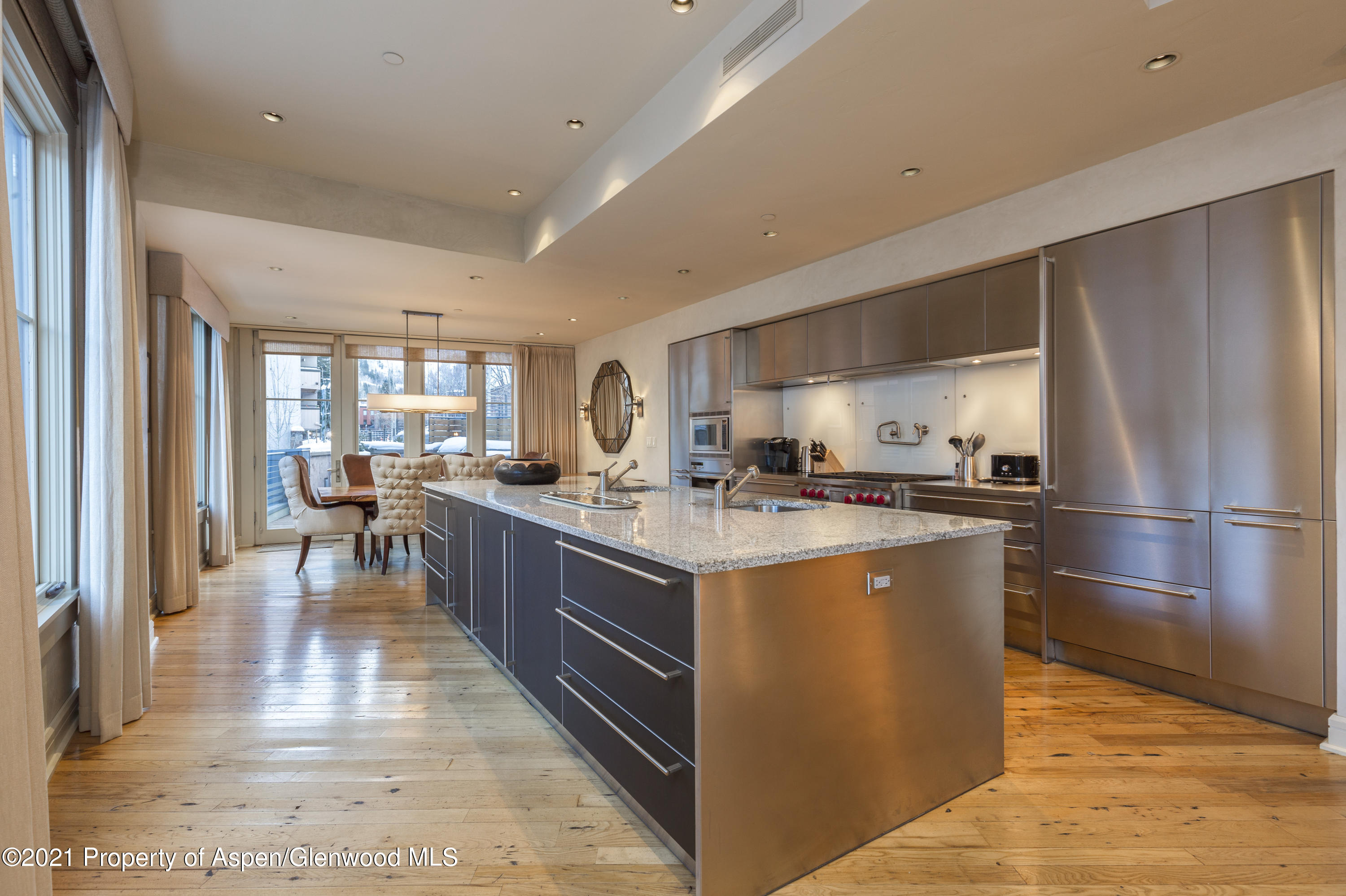 101 Founders Place, Unit 202 Aspen, CO 81611 - Photo 8 of 26 a kitchen with stainless steel appliances granite countertop a refrigerator a sink dishwasher a stove and a dining table with wooden floor