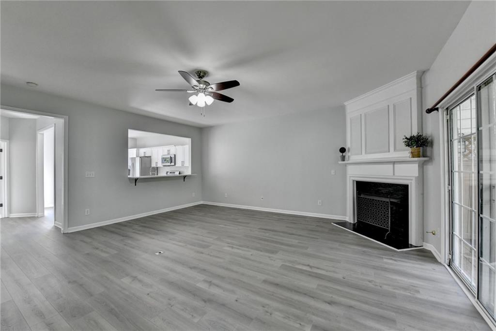 3977 Howell Park Road Duluth, GA 30096 - Photo 13 of 25 an empty room with wooden floor a fireplace and windows