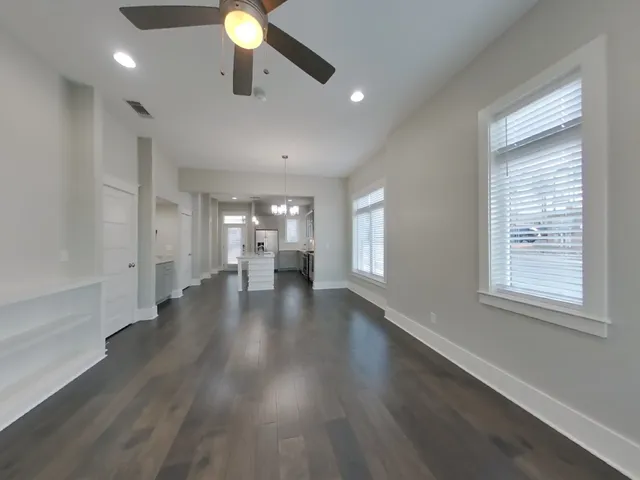 a view of an empty room with window and wooden floor